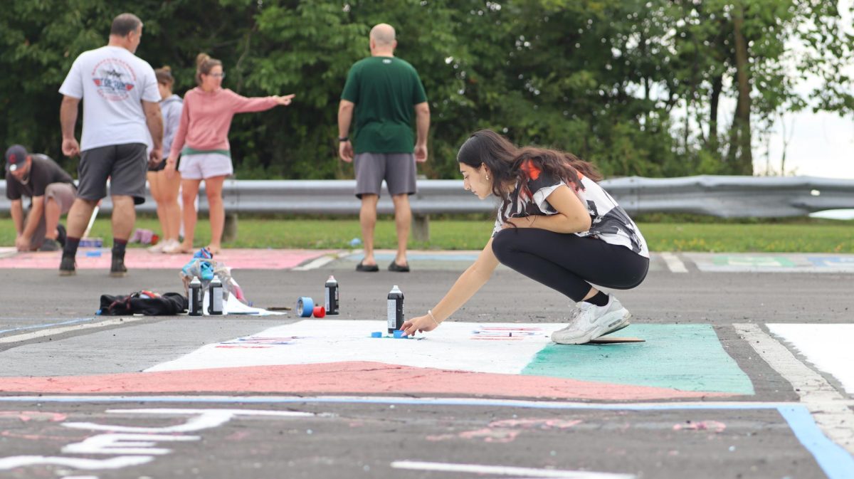 Kadeja Awawda, senior, paints the parking spot she shares with her brother Abdul Awawda, senior.